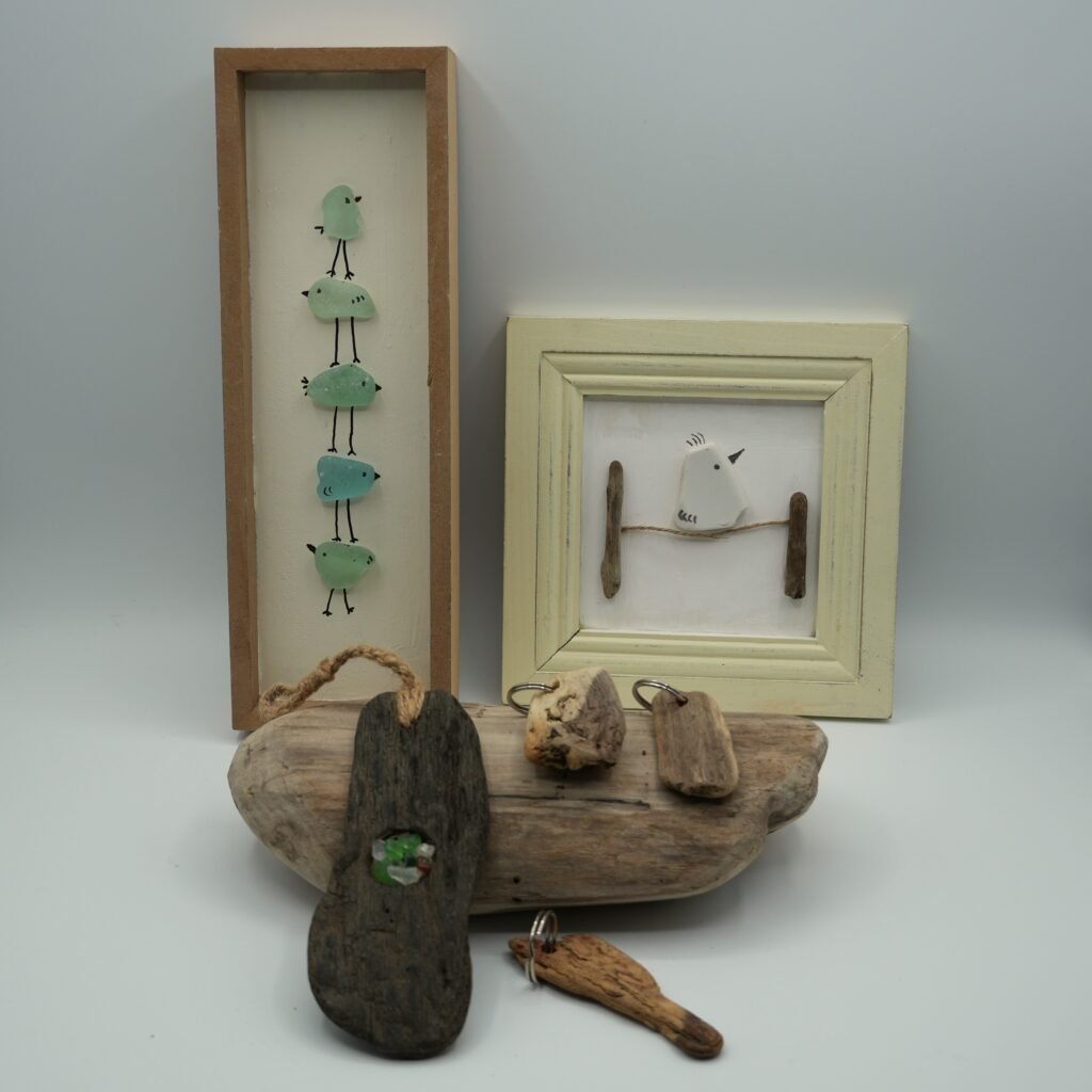 collection of driftwood and beach glass artwork, keychains, and a suncatcher
